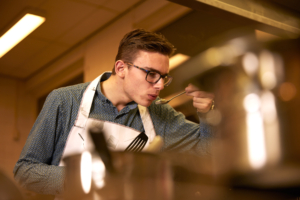 man proeft eten uit pan