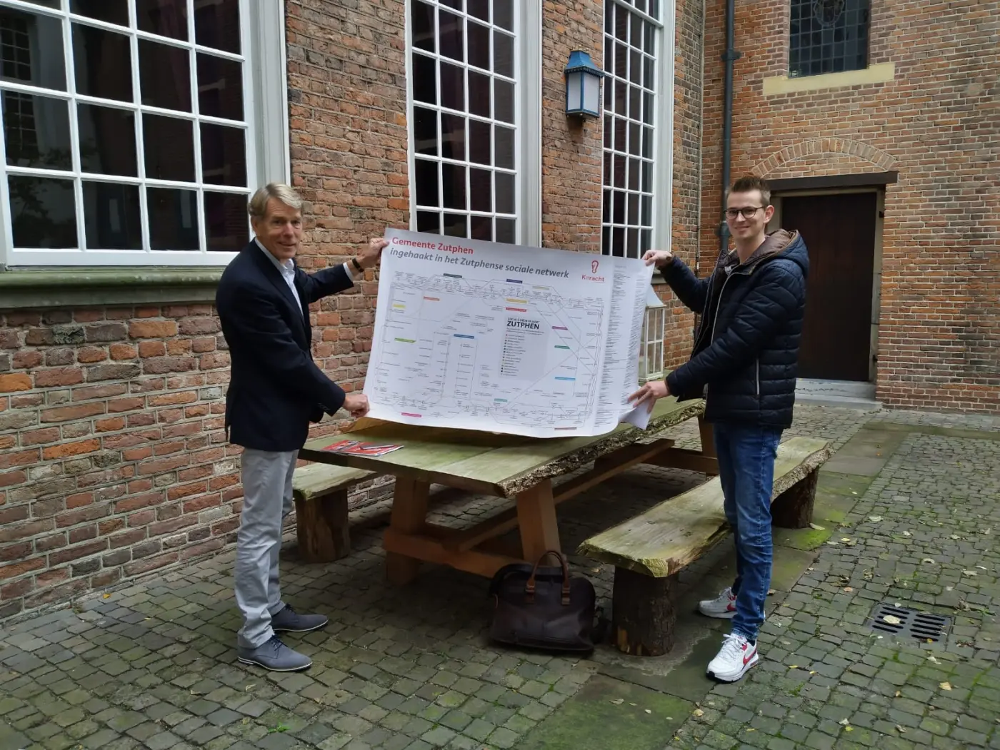 voorzitter biedt metrokaart aan aan de wethouder